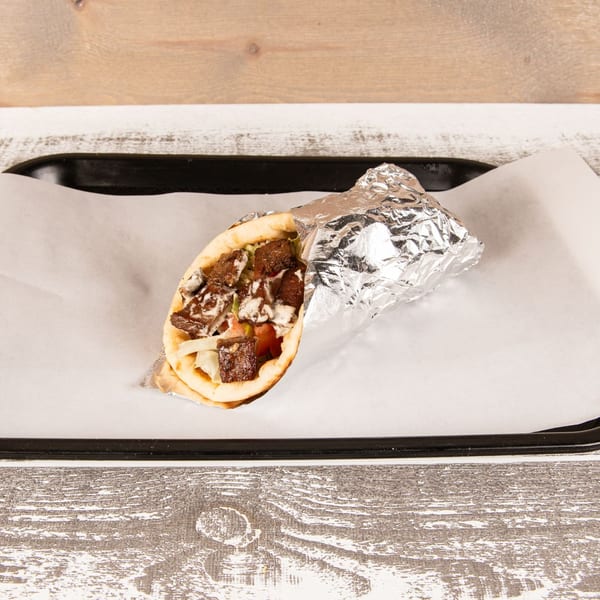 A partially unwrapped gyro with meat, onions, and sauce on a black tray with white paper.